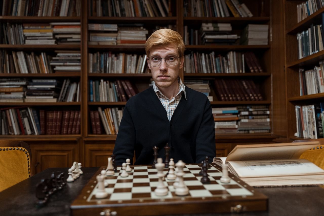 Services Portrait of a man playing chess in a library, highlighting concentration and strategy.