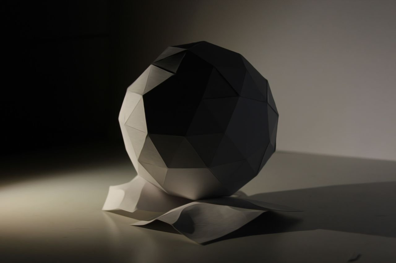 Services Minimalist geometric sculpture under artistic lighting, emphasizing shape and shadow.